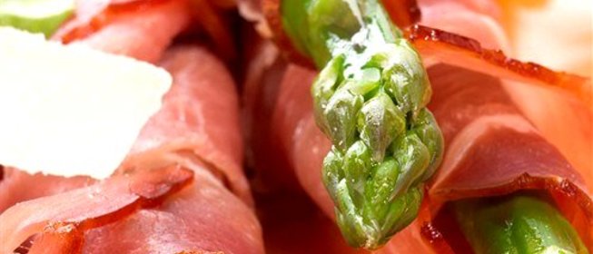 Спаржа, завернутая в ветчину серрано, с листьями салата, миндалем и виноградом